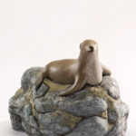 A serene sea lion atop mossy rocks - a custom cremation urn by Une Belle Vie artists